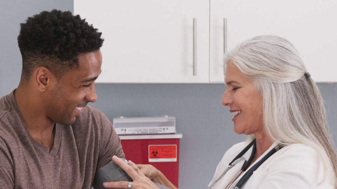 Mature white female physician checking male patients blood pressure at clinic