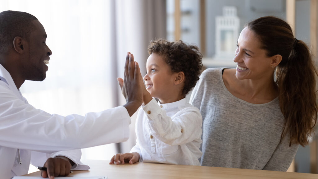 Servicios pediátricos, médico afroamericano sonriente en clínica médica con paciente sonriente y su madre