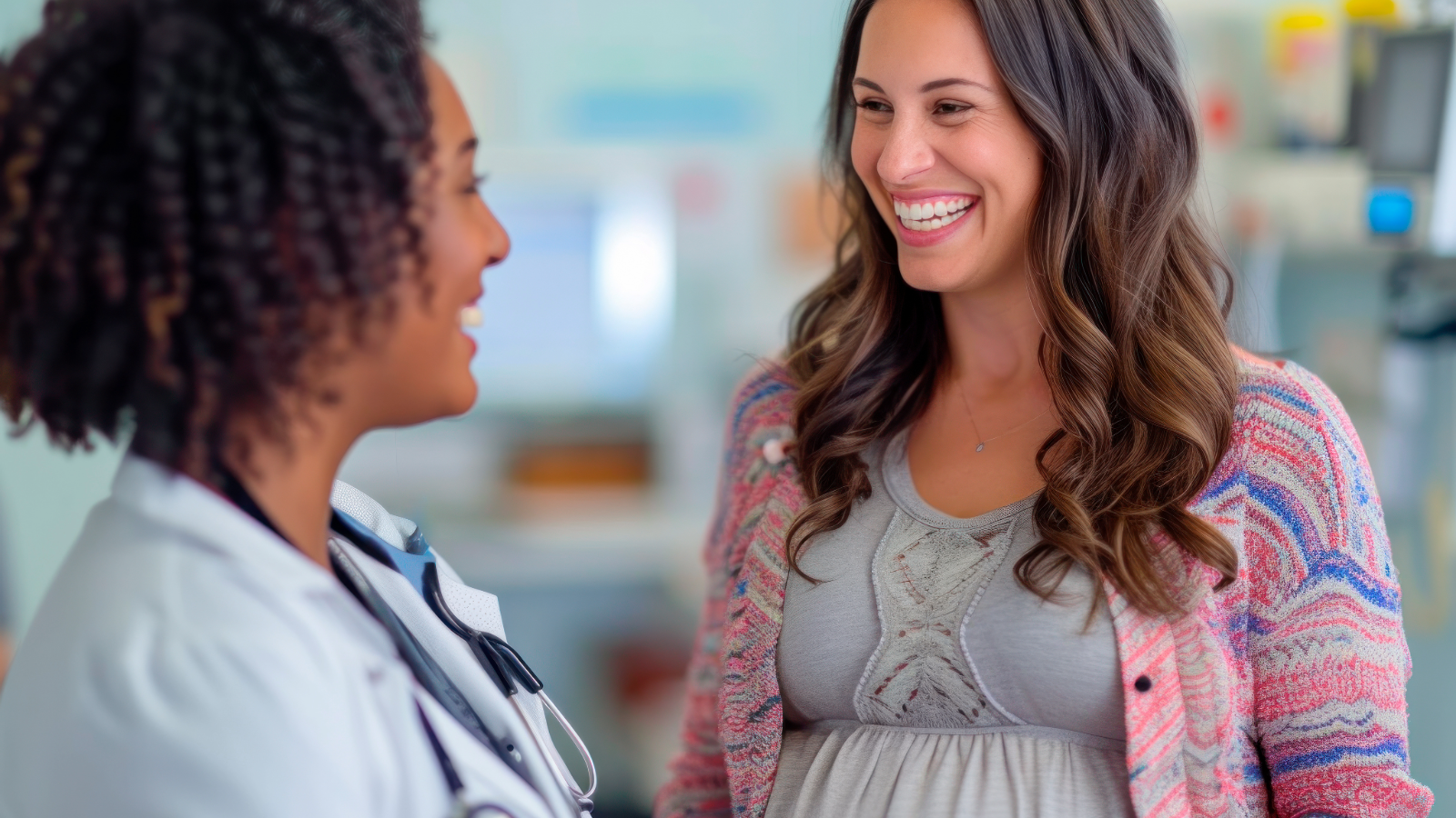 Smiling pregnant woman speaking with a female doctor during a women’s health care visit